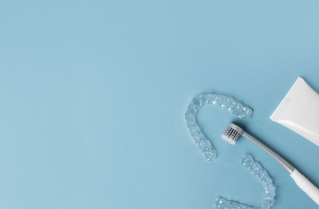 A toothbrush and clear dental retainer on a blue surface.